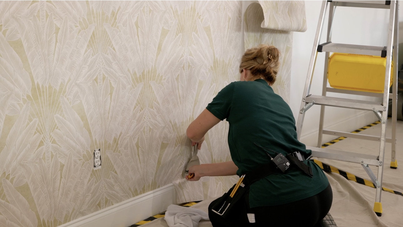 Professional installer applying patterned wallpaper to a wall